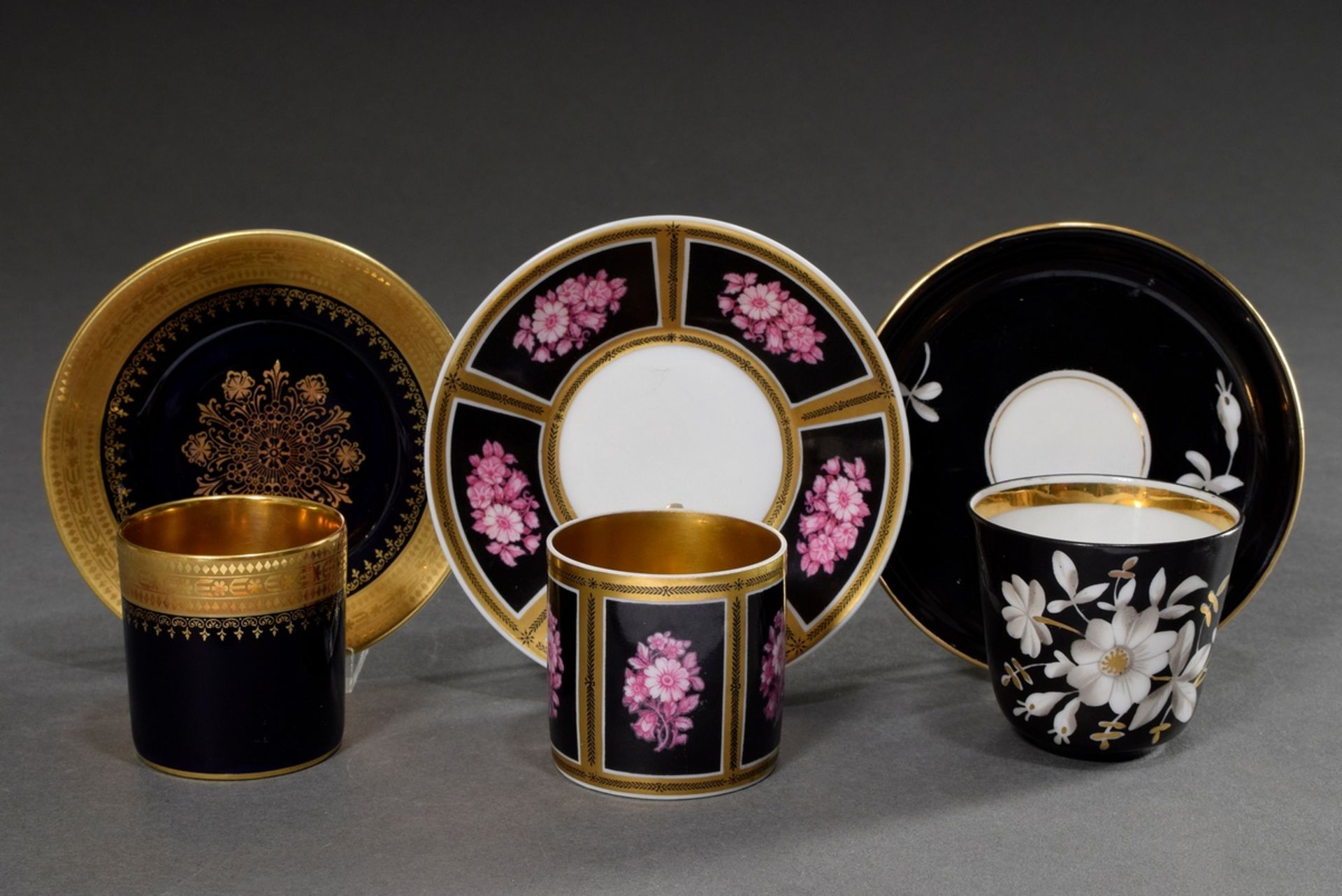 3 Various porcelain mocca cups/saucers with different floral and ornamental gold decorations on a b