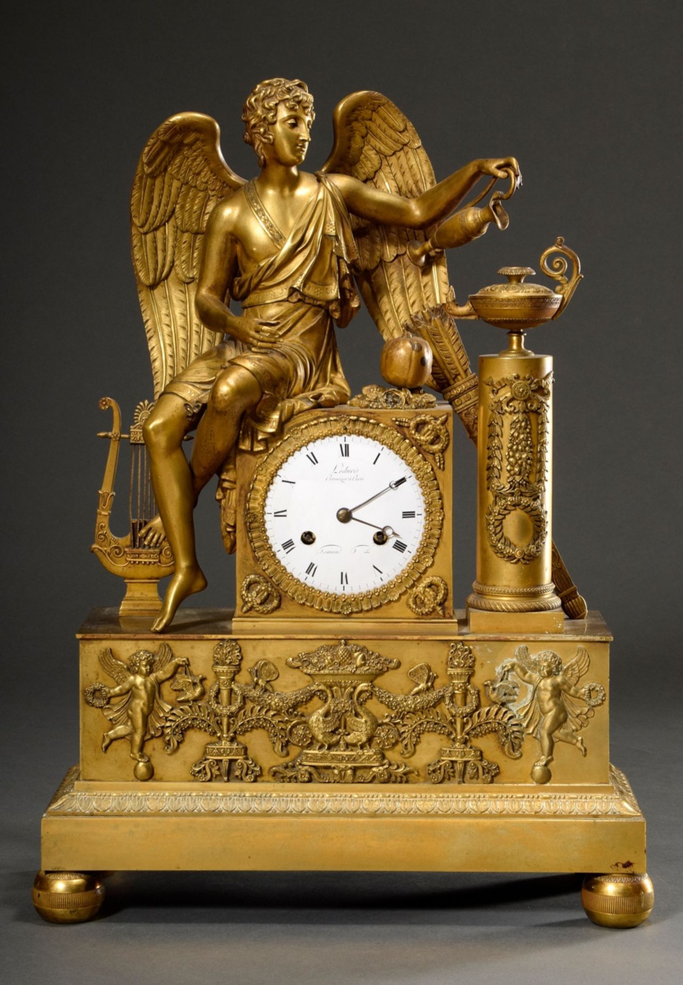 Französische Empire Prunkpendule „Amor gießt Öl ins Feuer“, feuervergoldete Bronze, Emaille Zifferb