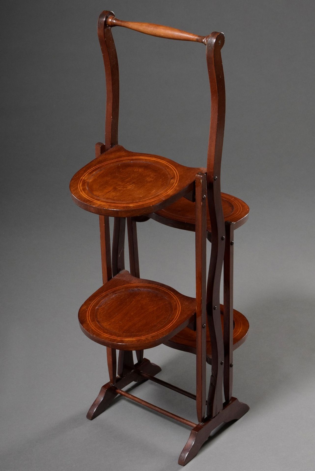 Mahogany cakestand with ribbon inlays, turned frame and two folding plate stands on each side, c. 1