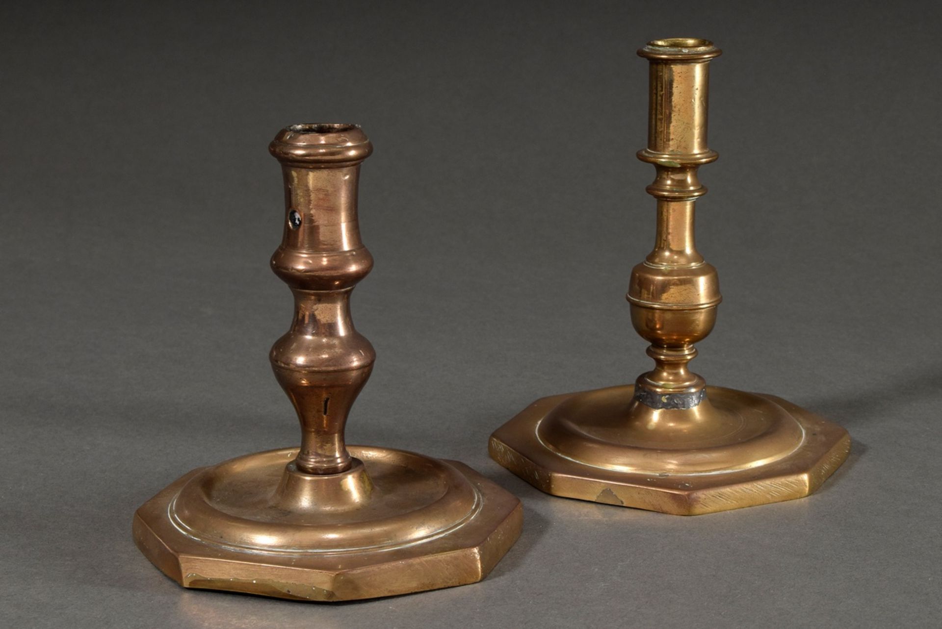 Pair of bronze candlesticks with different shaped baluster stems on wide octagonal feet, h. 13,5/15
