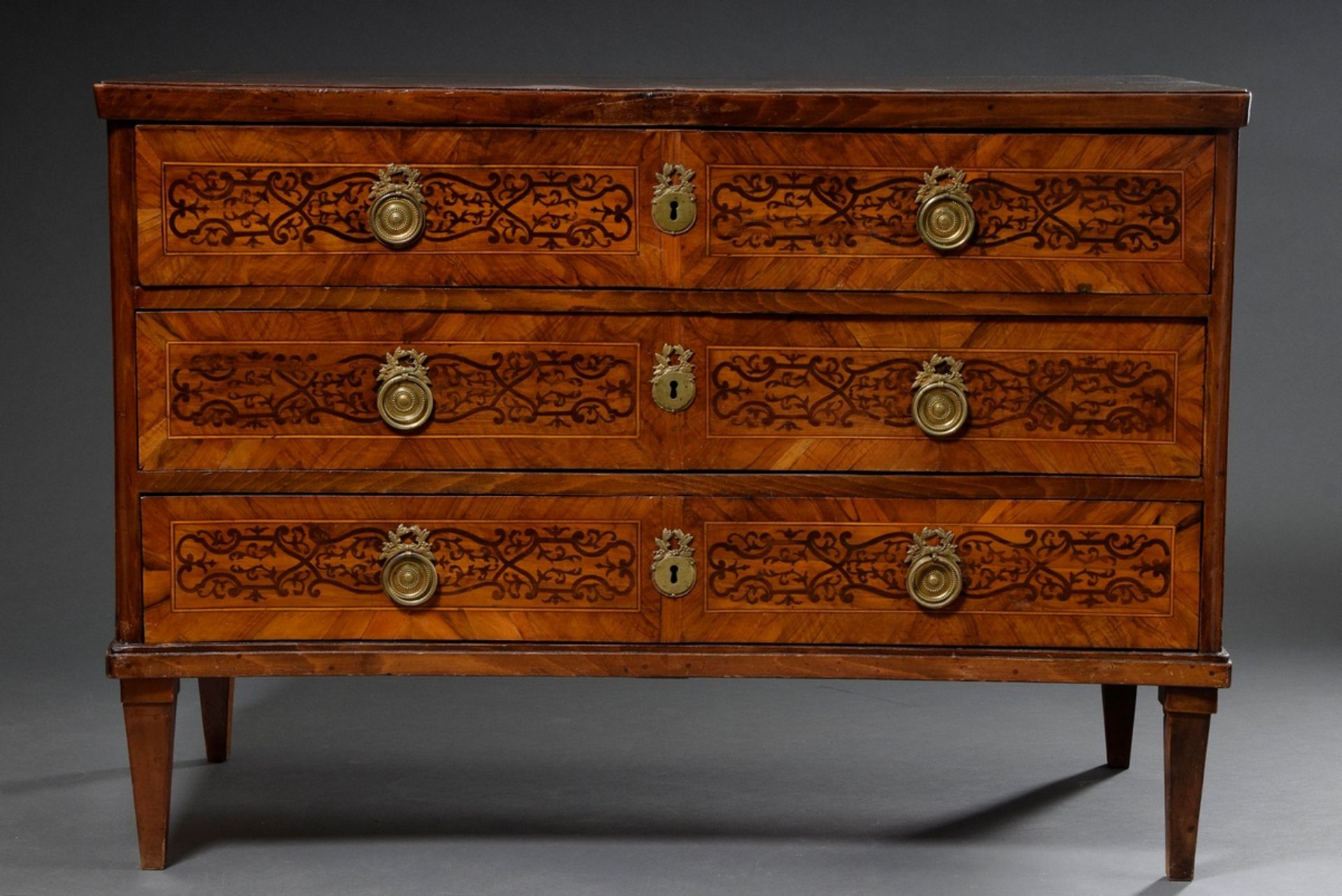 Classicist chest of drawers in strict façon on pointed legs with concave front, ornamental inlays o