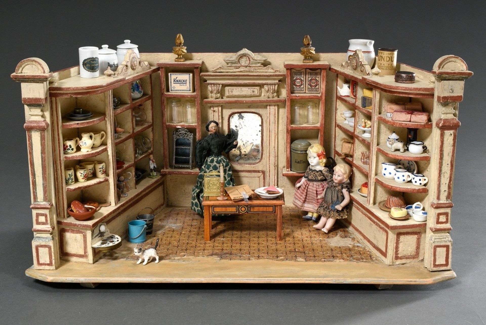 Dolls' shop with dolls and rich interior: e.g. pewter plates, glass bottles, porcelain jugs, around