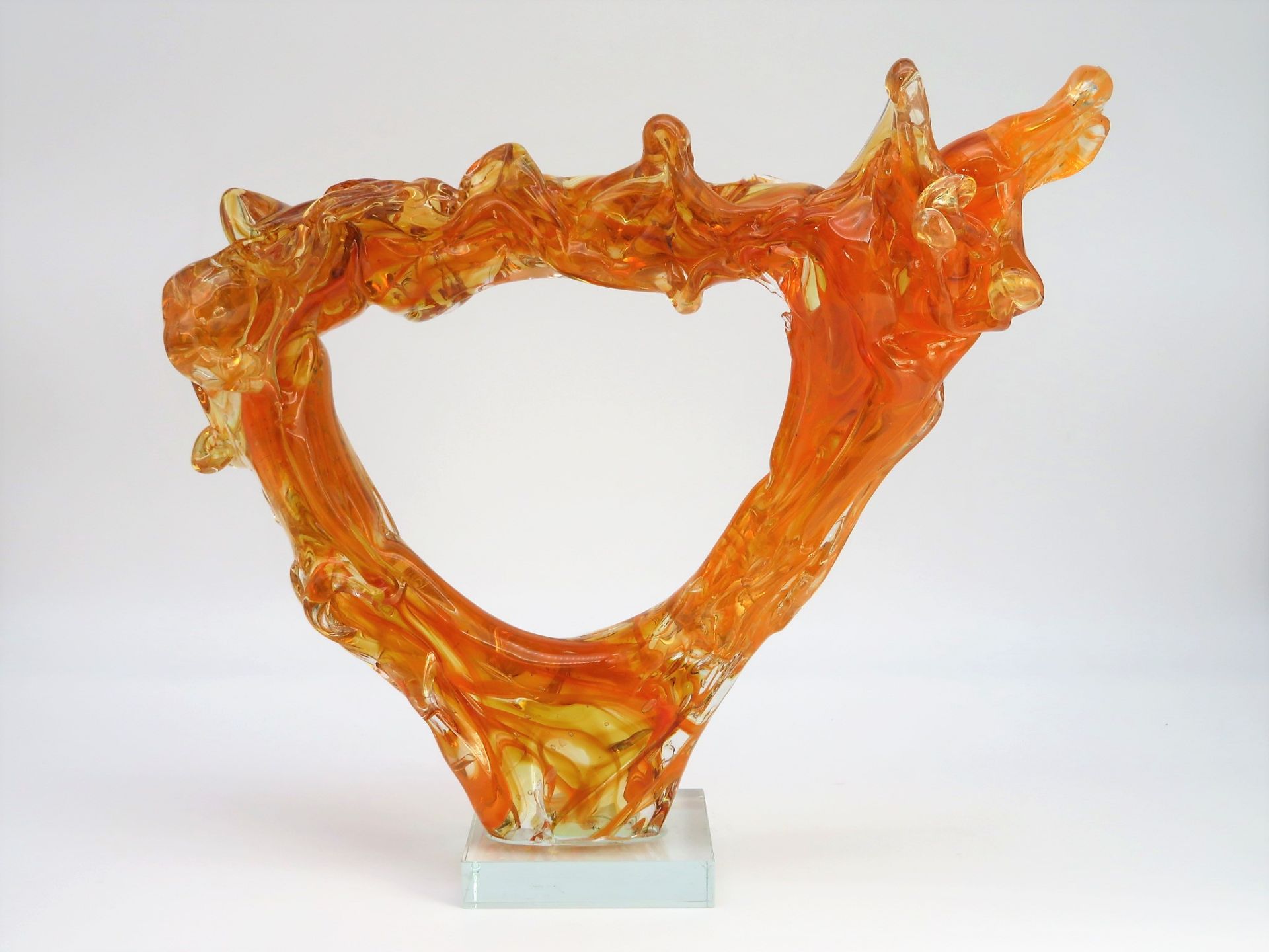 Designer-Glasobjekt in Form einer Wasserfontäne, orangefarben eingefärbtes Glas, auf gläsernem, tra
