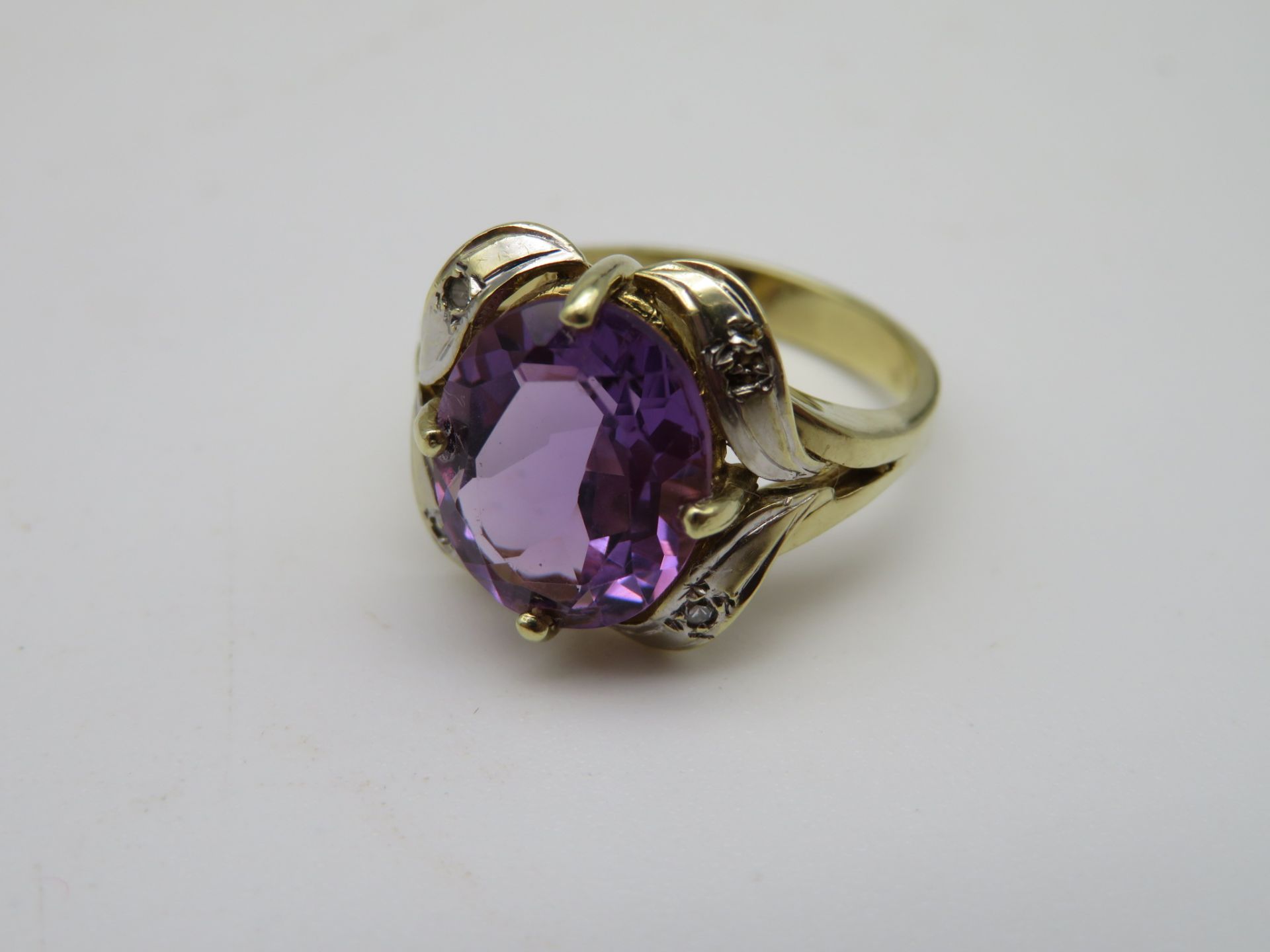 Damenring, durchbrochen gearbeitete, geschwungene Schauseite mit ovalem facettiertem Amethyst, 3 Di