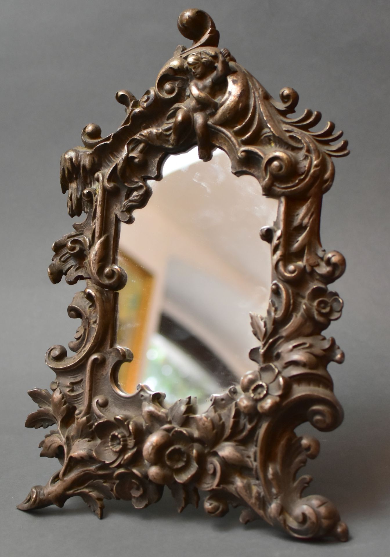 Aufstellspiegel, um 1880, Eisenguß, floraler, plastischer Rahmen mit Putto als Spiegelkrone,