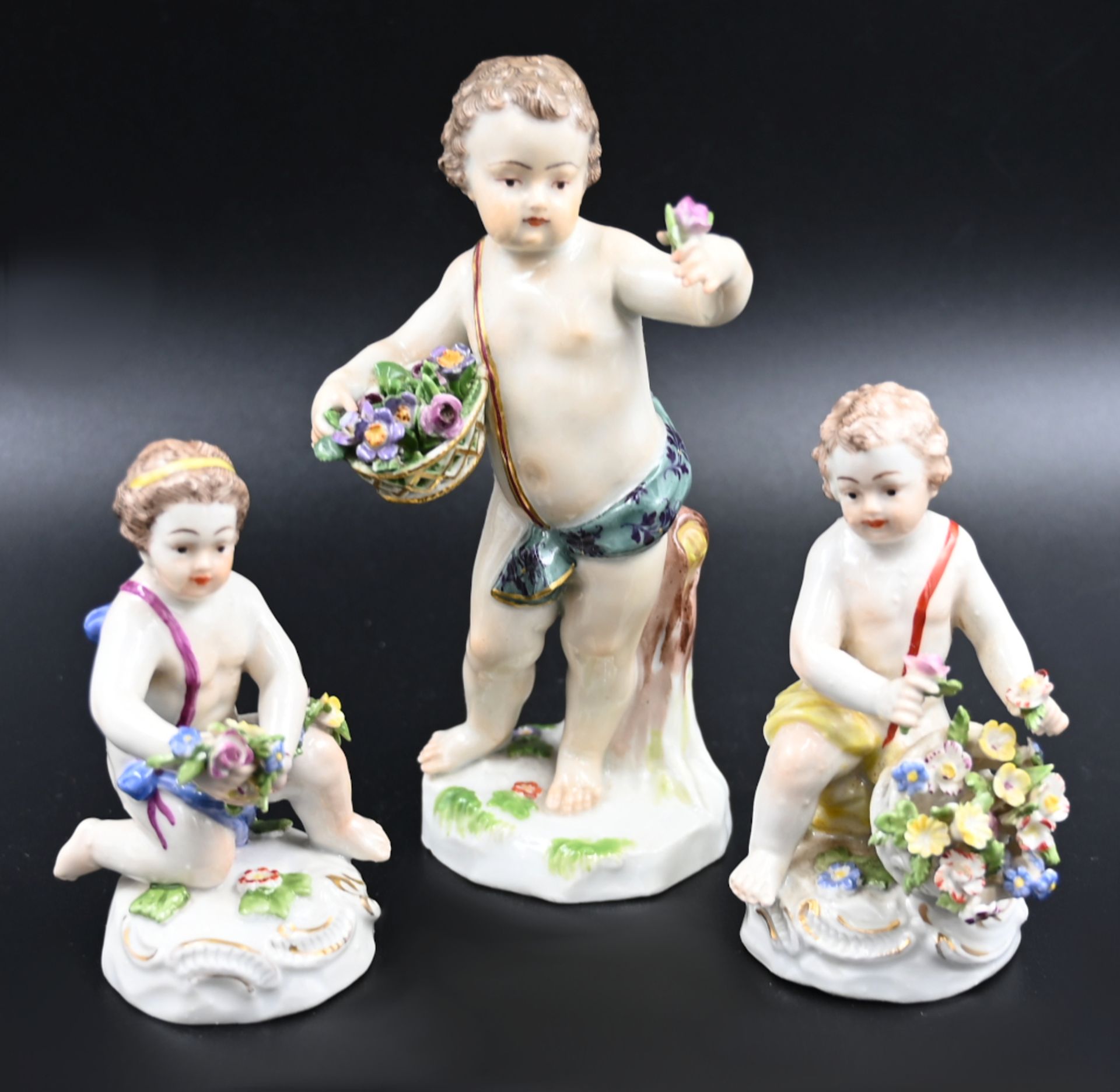 3 Figuren Porzellan MEISSEN, LUDWIGSBURG, "Putti mit Blumenbouquets", bemalt z.T. goldstaffiert,