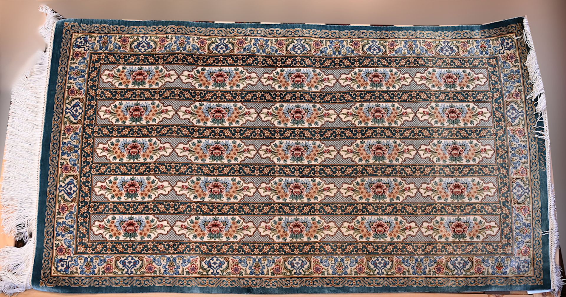 1 Orientteppich Seide 20. Jh. grüngrundig mit 5-facher Kartuschenreihung, signiert, ca. 125x69cm, Fr