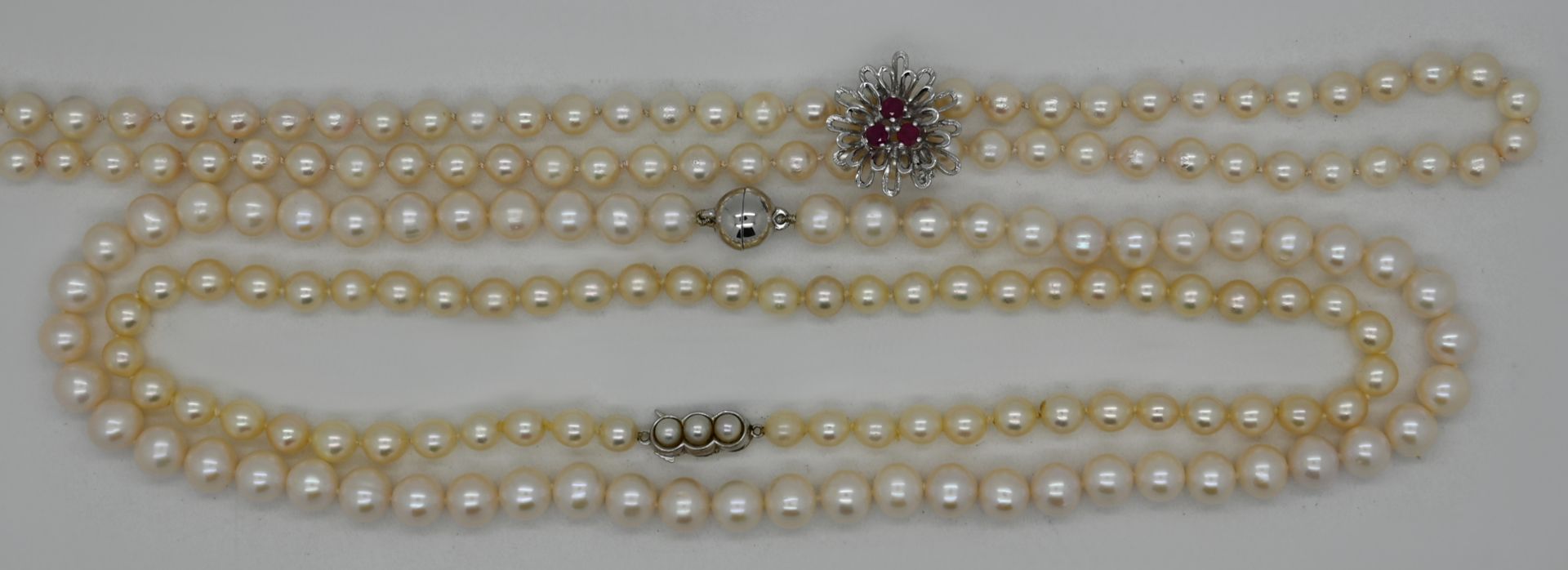 3 Perlenketten, z.T. mit Perlclip WG mit Rubinen und Verschluss GG/ WG je 14ct., sowie Magnetverschl