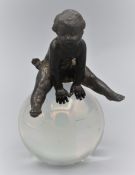 Fast unbekleidetes Kind auf einer Glaskugel, Miniatur-Skulptur um 1920, mundgeblasene Glaskugel mit