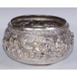 A large Burmese silver metal bowl, repousse chased in bold relief with a hunting scene, deities,