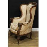 A 19th century softwood fauteuil à oreilles, the wingback carved with a border of ribbons, manchette