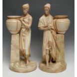 A pair of Worcester figures, Nubians, modelled by James Hadley, both standing in Eastern dress