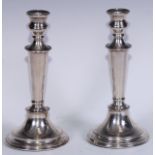 A pair of Elizabeth II silver table candlesticks, campana sconces, tapered pillars, spreading and