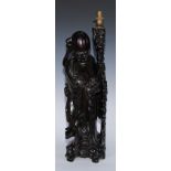 A late 19th century Chinese hardwood figure, now as a table lamp, of an elder holding a staff,