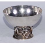 An Arts and Crafts silver circular pedestal bowl, the base cast with alternating Reynolds angels and
