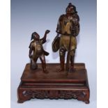 A Japanese brown and gilt patinated bronze group of a Cormorant fisherman and boy, he stands holding