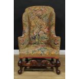 A 19th century wingback armchair, in the William and Mary taste, shaped back, outswept arms,