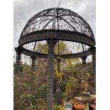 A large classical cast iron garden gazebo, the domed wrought iron canopy above a deep collar cast