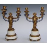 A pair of Neo-Classical ormolu and white marble two-light candelabra, each cast as a scantily clad