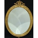 A 19th century giltwood and gesso oval looking glass, the bevelled mirror plate crested by a