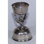 A 19th century continental silver wager or bridal cup, embossed floral hinged top bowl above figural