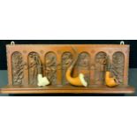 An unusual early 20th century wall mounted pipe rack, for six pipes, carved in relief with tobacco