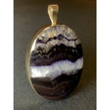 A blue john fluorite pendant, the reversible oval pendant banded with vibrant and deep purple,
