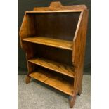 An early 20th century Arts & Craft oak student bookcase, shaped deeper top above two open shelves,