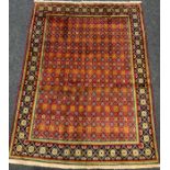 A Baluch rug, having a central field of stylised flowers on a red ground, enclosed within a margin