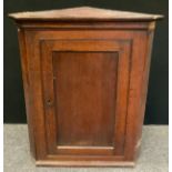 A George III oak splay front wall hanging corner cupboard, rectangular panel door enclosing two