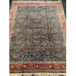 A hand made Hereke rug / carpet, woven in shades of red, turquoise, and blue with a central field of