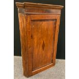 A George III oak corner cupboard, moulded cornice, the field panelled door inlaid with mahogany
