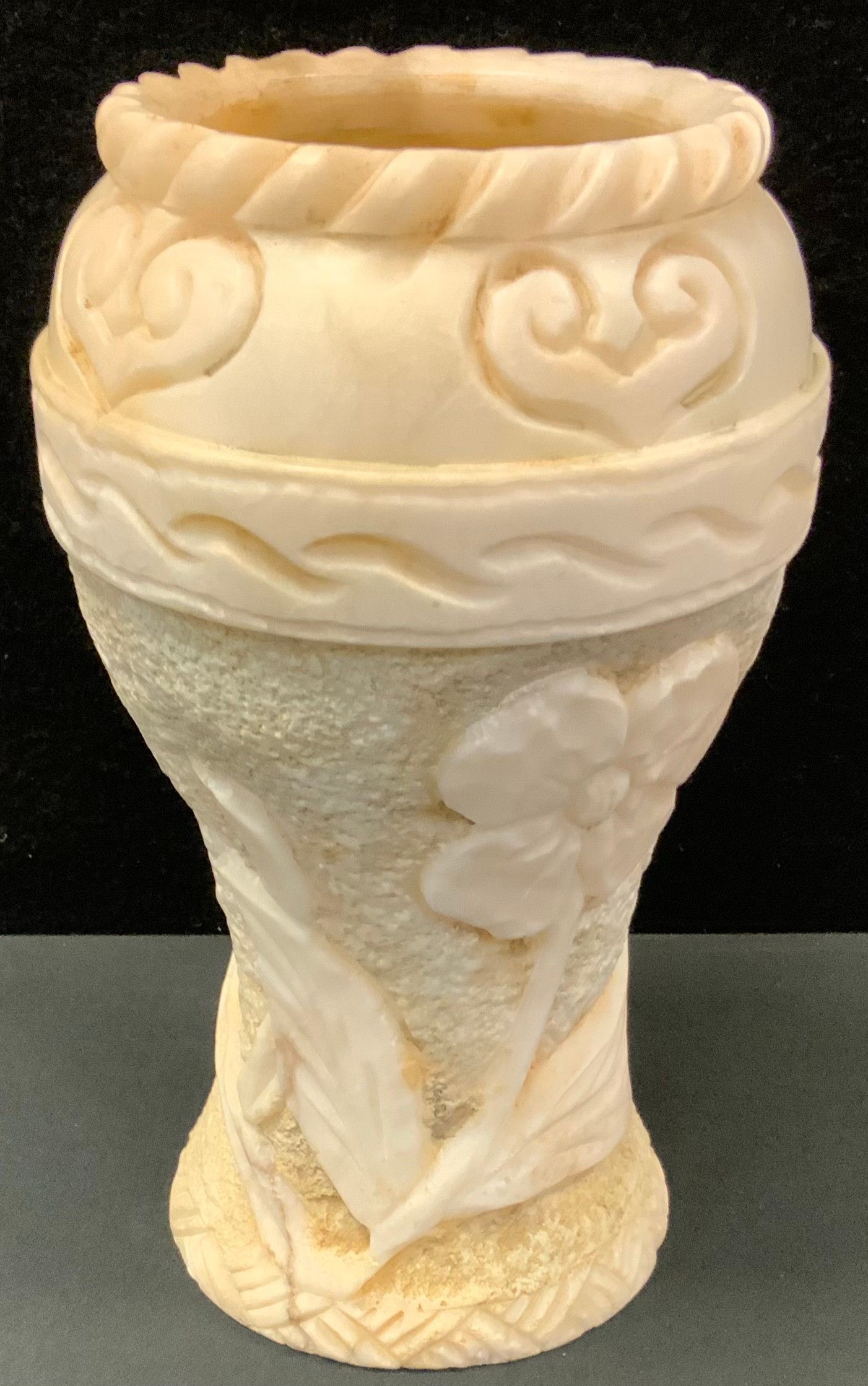 A large veined creamy white stone vase, possibly marble, floral ruff textured body beneath smooth