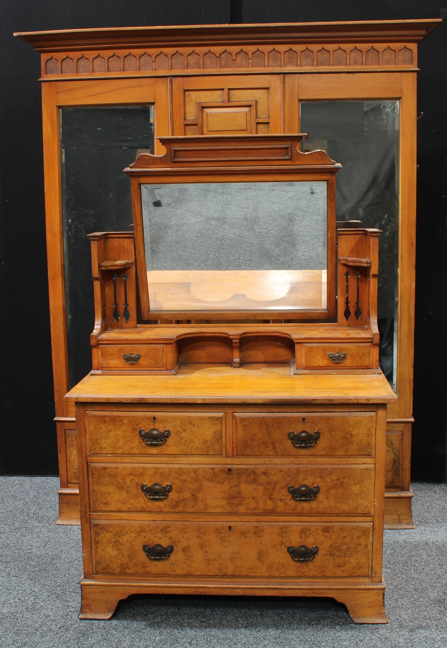 An Arts & Crafts period walnut accented two piece bedroom suite, comprising a triple-door wardobe