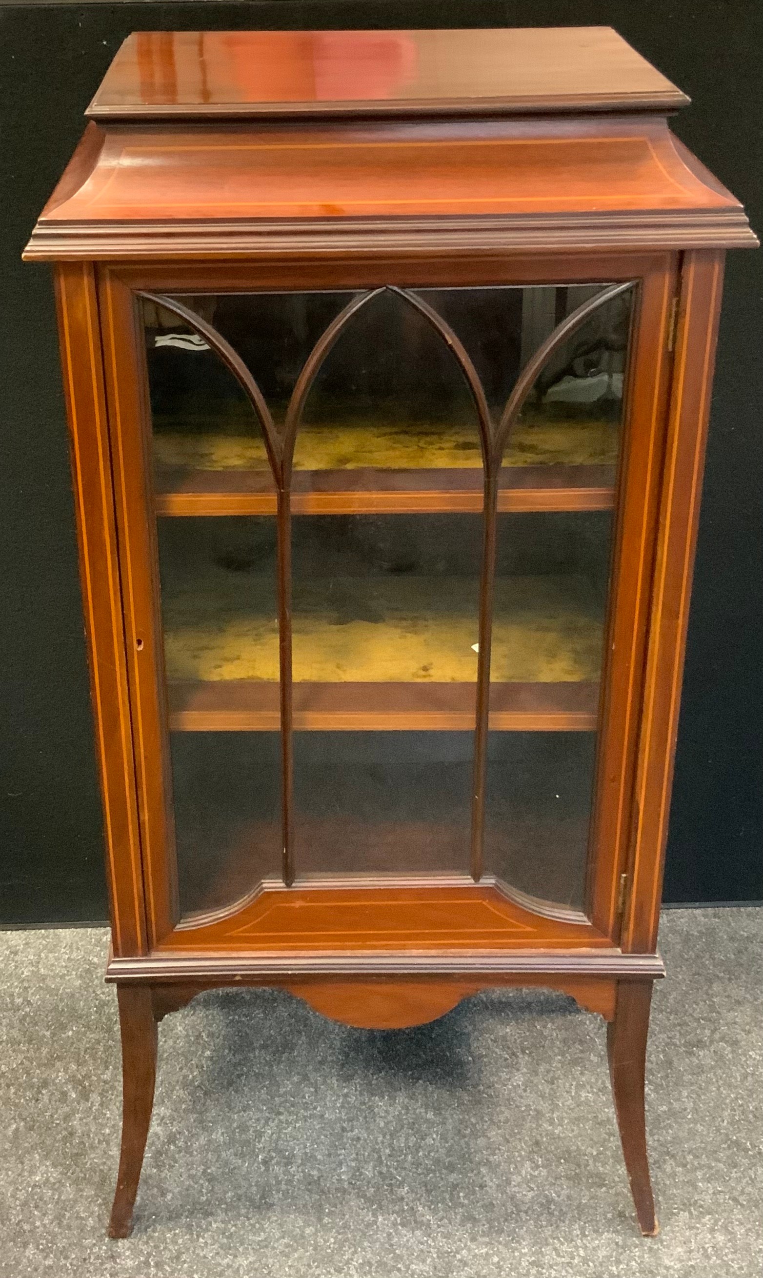 An Edwardian mahogany cabinet of small proportions, single glazed door enclosing two tiers of