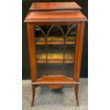 An Edwardian mahogany cabinet of small proportions, single glazed door enclosing two tiers of
