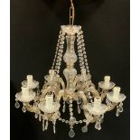 A late 19th/ early 20th century eight branch chandelier, shaped scrolling arms, faceted droplet