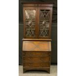 An early 20th century oak bureau bookcase, outswept cornice above a pair of stained astragal glass