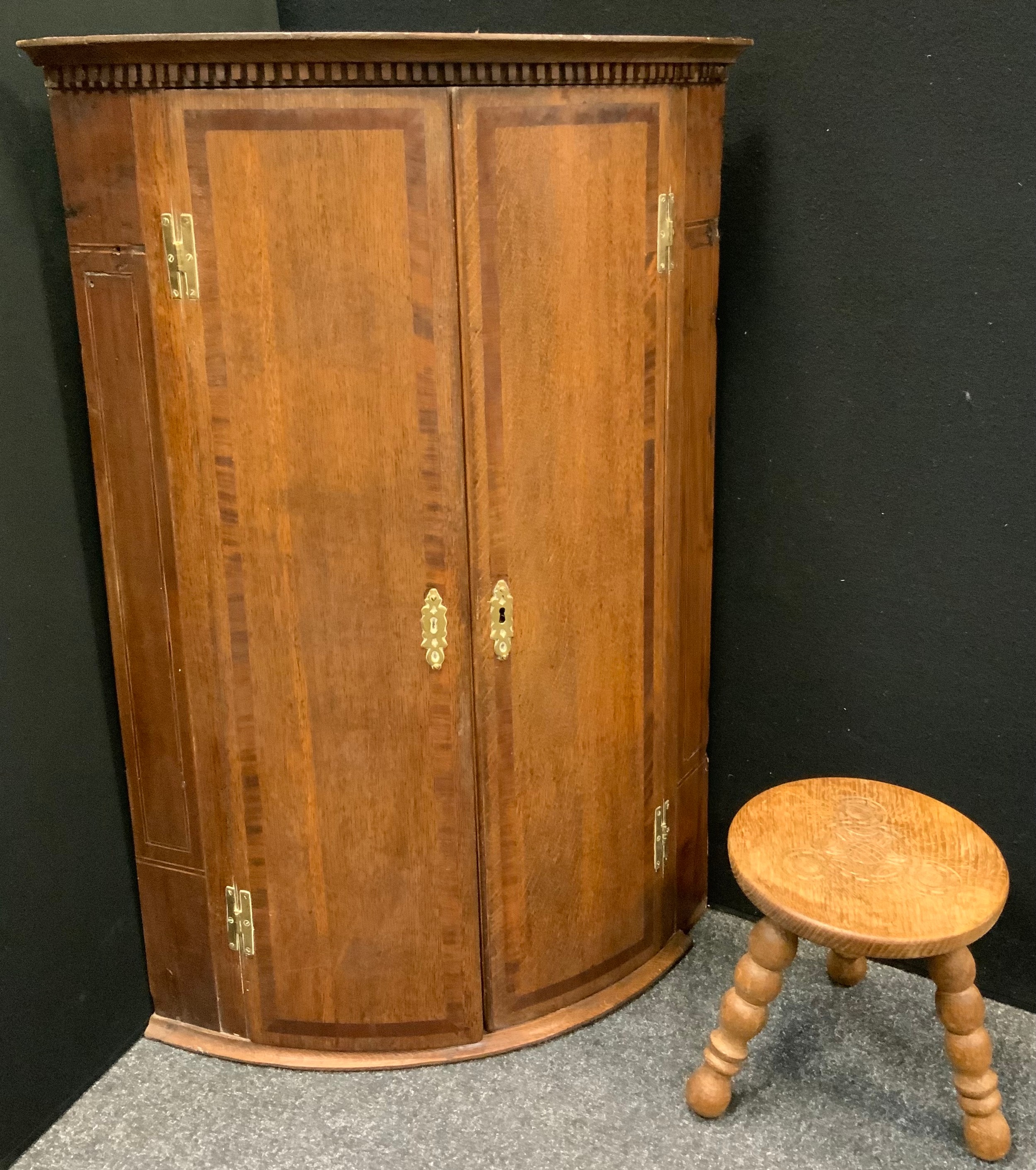 A George III mahogany cross banded oak bow front corner cupboard, brass H hinges, 97cm high, 67cm