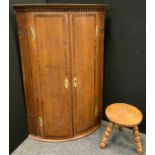 A George III mahogany cross banded oak bow front corner cupboard, brass H hinges, 97cm high, 67cm