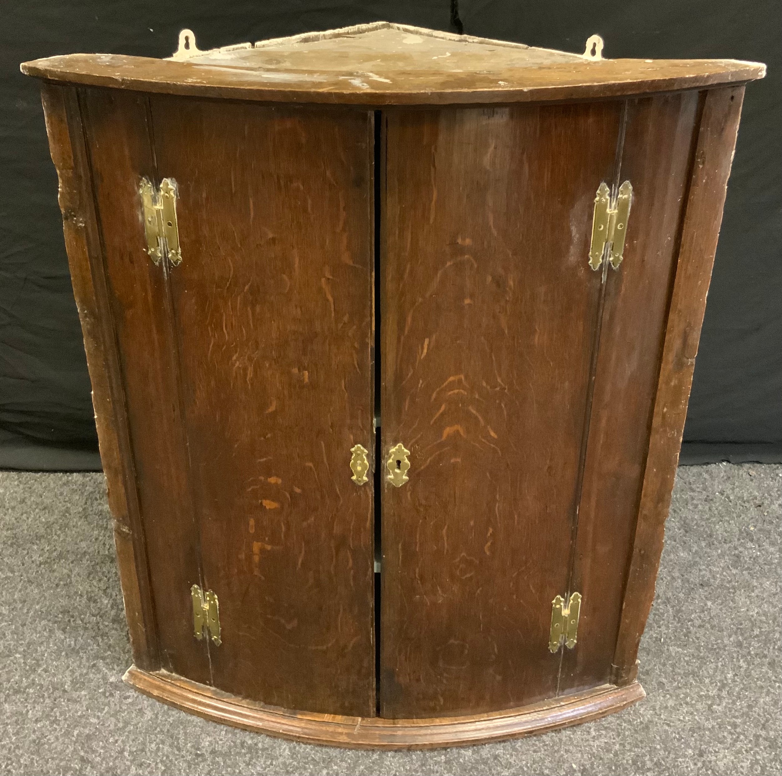 A George III oak wall hanging corner cupboard, 86cm high, 74cm wide.