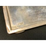 A Persian silver coloured metal cigarette case, the front relief decorated with traditional