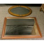 An early 20th century oak framed oval wall mirror, bevelled glass, 88cm x 63cm; another, (2)