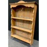 A pine wall hanging shelf, shaped cornice, 77cm high, 54cm wide