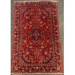 An antique, hand-made, Persian Kashan rug / carpet, woven in tones of deep red and blue, 202cm x