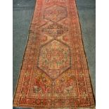 A Middle Eastern woollen rug / carpet, in tones of red, blue and cream, 500cm x 195cm