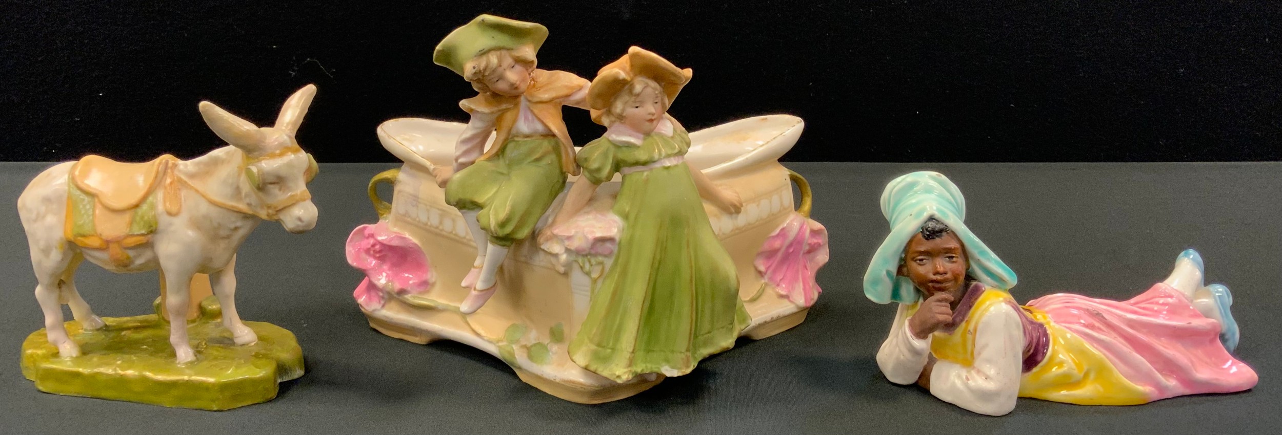 A Royal Dux figural bowl of triangular form with two figures boy and girl, 16cm x 24cm, pink