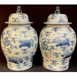 A large pair of Chinese floor standing temple vases and cover, painted in blue and white, lion