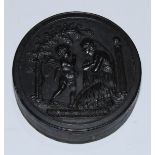 A 19th century pressed horn circular snuff box, the push-fitting cover in relief with Cupid and