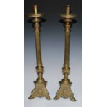 A pair of Continental Baroque brass candlesticks, tall sconces, fluted campana saucer shaped drip